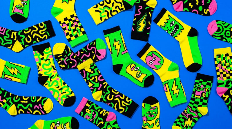 Funky Angry Toast crew socks flat-lay in green, yellow and pink on an electric blue background